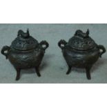 A pair of antique Chinese bronze censers with relief dragon and cloud design and rooster finial to