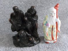 A carved Chinese hardwood statue with three figures with a porcelain hand painted Chinese figure