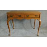 An early 20th century satin walnut Queen Anne style two drawer writing desk on cabriole supports.