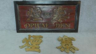 A Chinese red and golden sign reading 'Opium Den' together with two identical carved Chinese