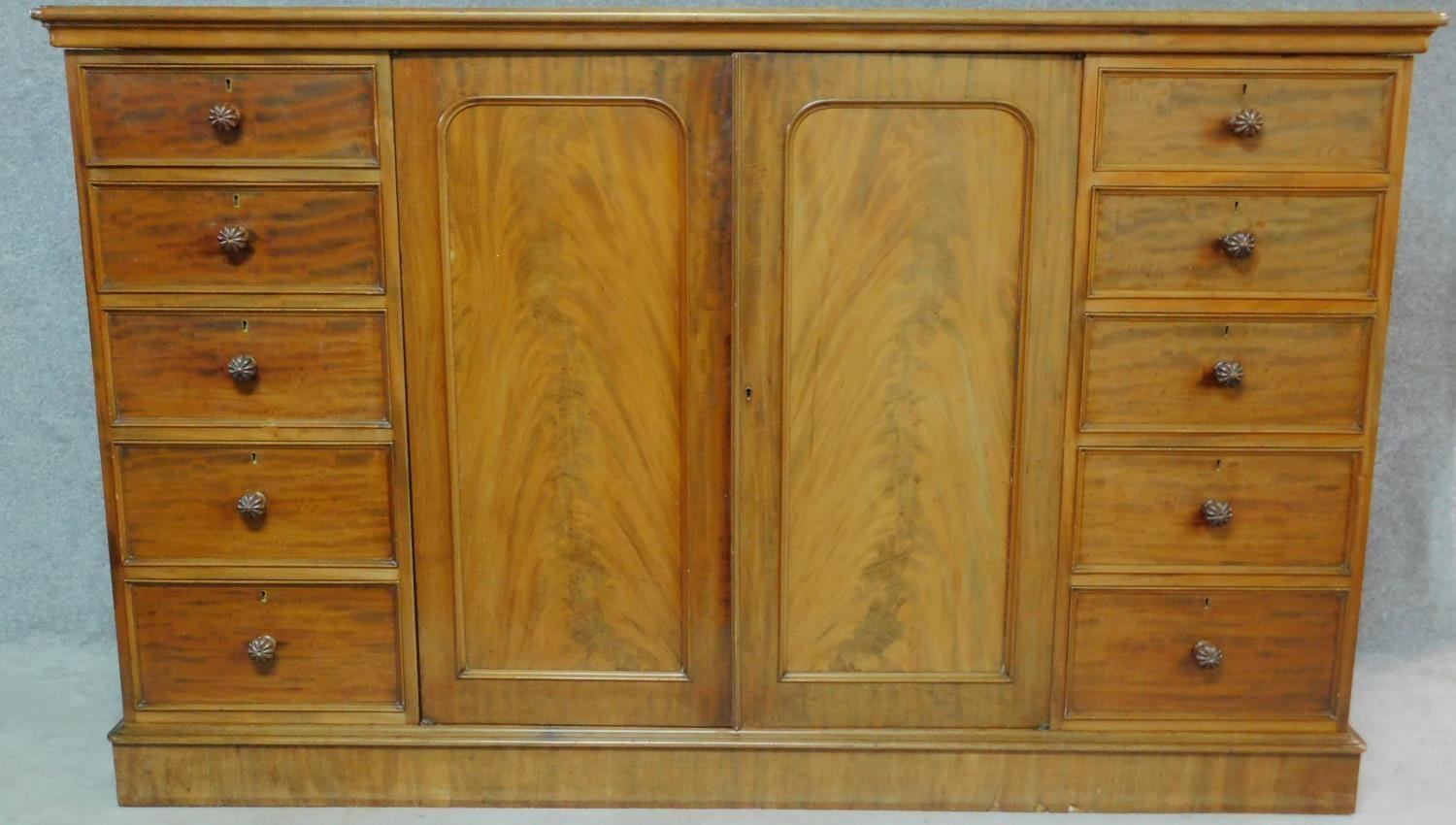 A Regency mahogany press cupboard with fitted central panel doors enclosing linen slides, flanked by