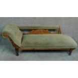 A Victorian beech framed chaise longue decorated with floral carvings and raised on turned supports.