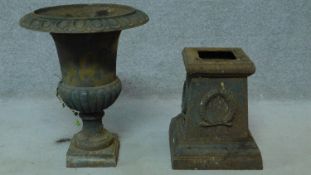 A cast iron urn and base with wreath motif and stylised geometric border. H.62cm