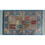 A Persian silk rug with repeating tile design with stylised floral motifs, within border with