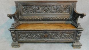 An 18th century Italian carved oak hall bench fitted hinged seating compartment on block scroll