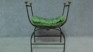 An Edwardian iron stool with green fabric pillow, twisted cast decoration and raised on