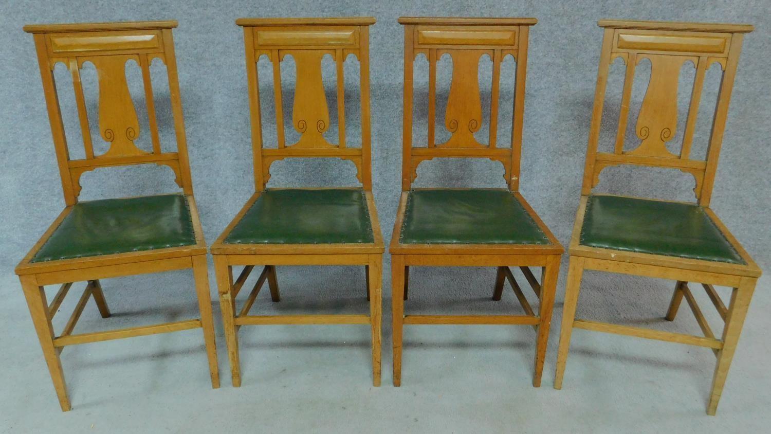 A set of four Art Nouveau oak chairs with carved back and green leather upholstery raised on