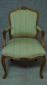 A Victorian oak armchair with floral carved details and green stripped upholstery, raised on