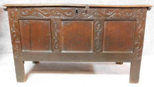 A 17th century panelled oak coffer with carved frieze on block feet. H.63 W.108 D.48cm