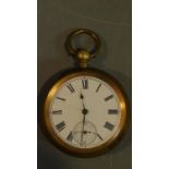 An antique brass pocket watch with bevelled glass and white enamel dial with black Roman numerals,