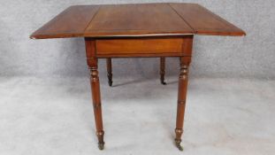 A 19th century mahogany drop flap Pembroke table on ring turned tapering supports terminating in