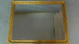 A rectangular gilt framed mirror with Rococo decoration. 136x106cm