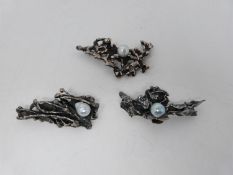 Two silver and one white metal and grey baroque pearl contemporary brooches. With secure hinged