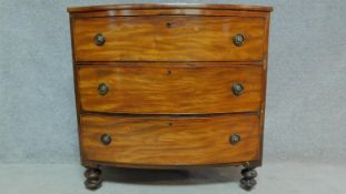 A Regency bowfronted chest of three long drawers raised on turned supports. H.91 W.92 D.49cm