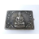 A vintage oriental silver cigarette case with Buddha and Thai demon relief design. Push catch