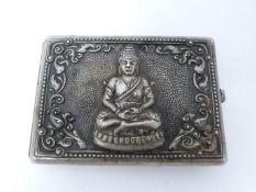 A vintage oriental silver cigarette case with Buddha and Thai demon relief design. Push catch