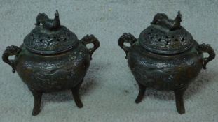 A pair of antique Chinese bronze censers with relief dragon and cloud design and rooster finial to