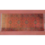 A 20th century Persian runner with four geometric medallions, on a terracotta ground, contained by