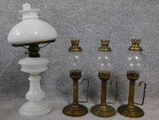 A milk glass converted oil lamp together with a set of three other brass detailed glass oil lamps.