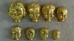 Eight antique brass boy and girl doll's head moulds, graduating in size. All with casting holes