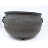 An antique Chinese bronze cauldron with two handles. On three tapering feet with two swing