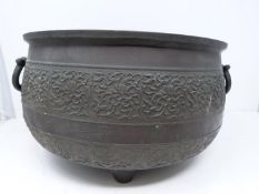 An antique Chinese bronze cauldron with two handles. On three tapering feet with two swing