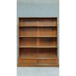 A Georgian mahogany open waterfall bookshelf fitted with two base drawers. H.133 W.107 D.30cm