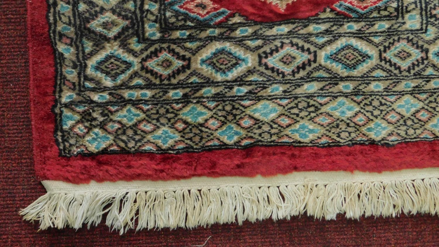 A Persian rug with triple pendant medallions, set on a rouge field with repeating geometric motifs - Image 3 of 4