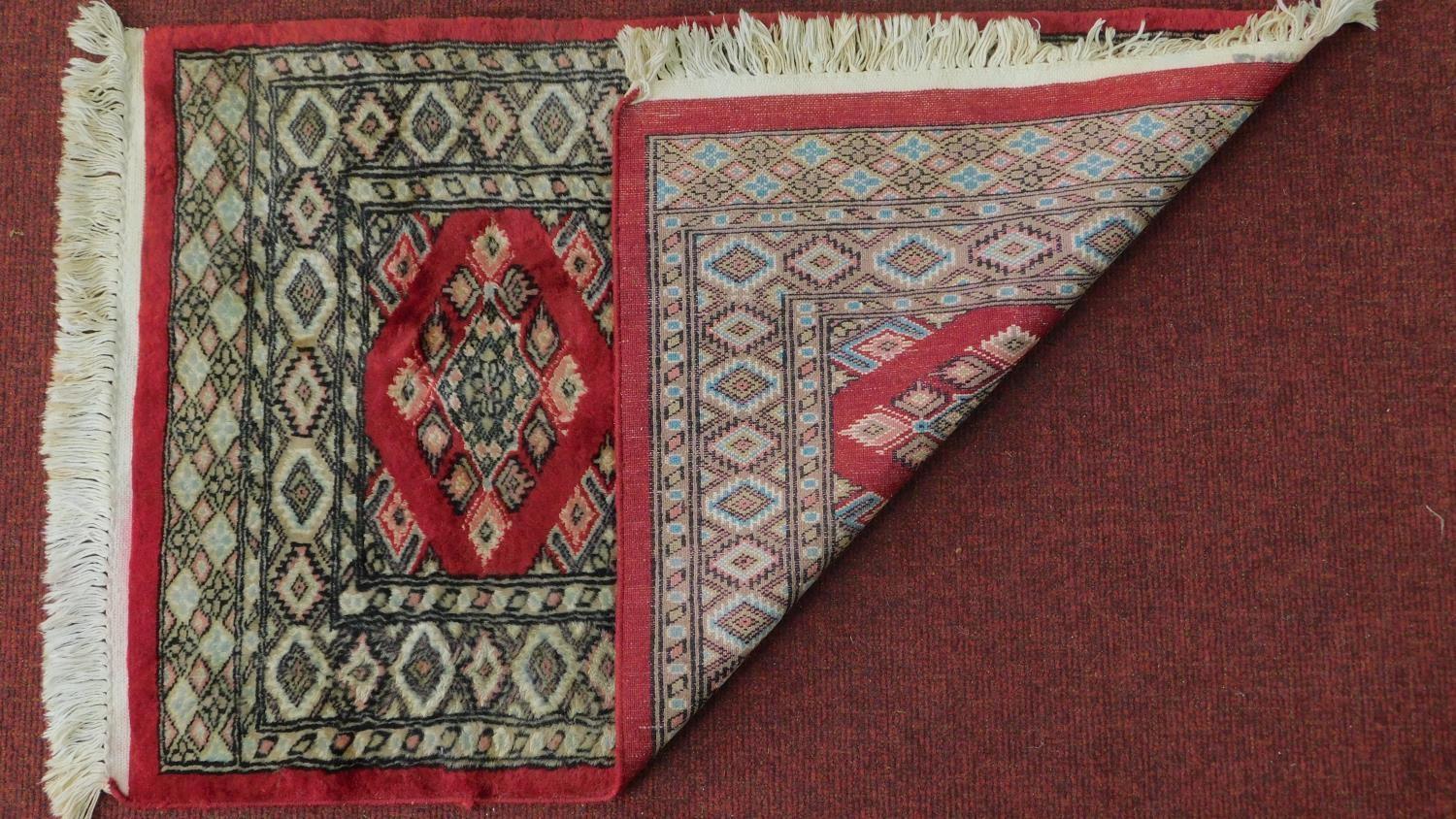 A Persian rug with triple pendant medallions, set on a rouge field with repeating geometric motifs - Image 4 of 4