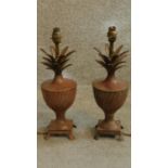 A pair of patinated metal pineapple shaped lamps on urn form bases with lion paw feet. H.41cm