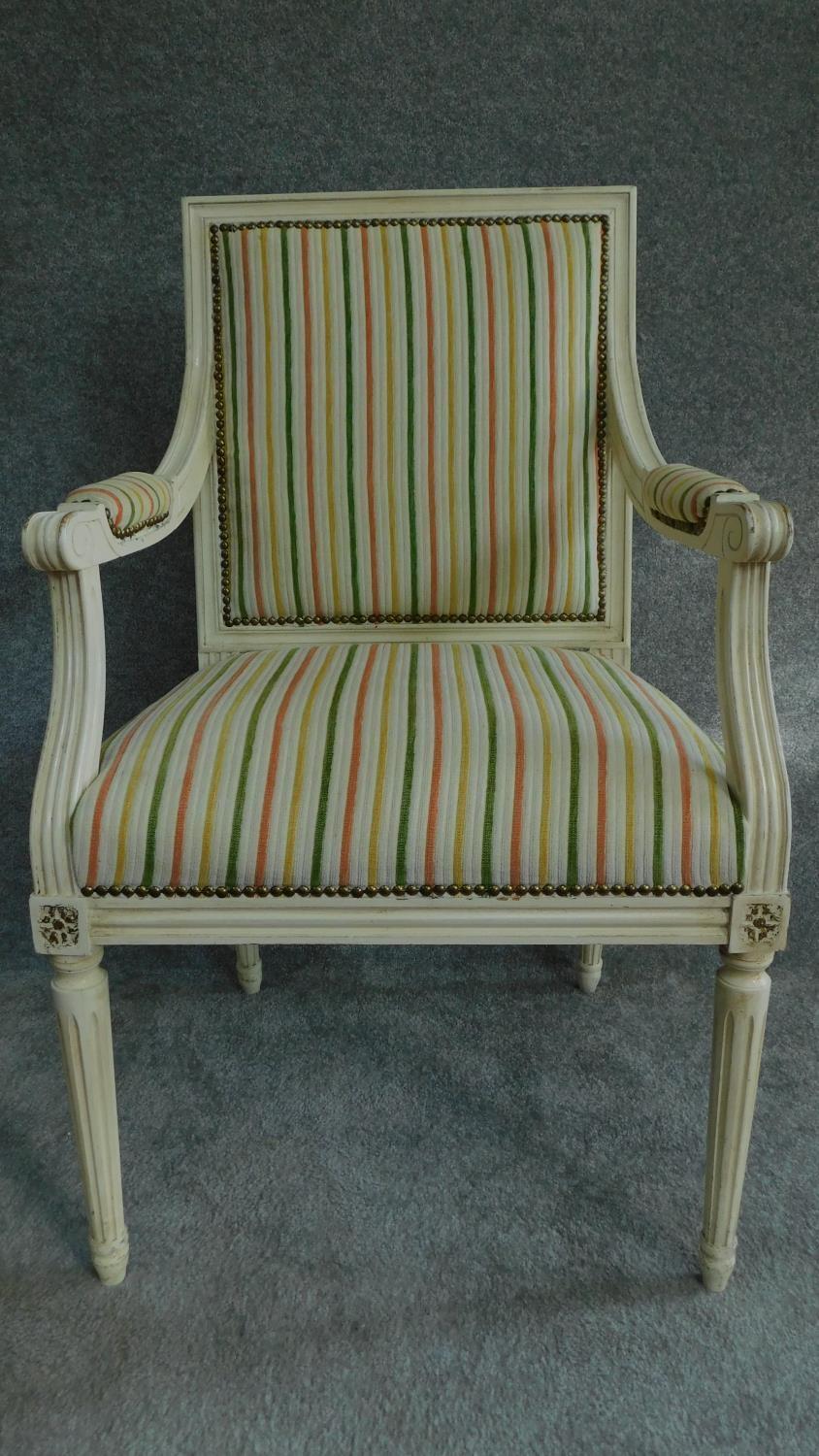 A Louis XVl style painted white armchair in striped upholstery and raised on tapering fluted