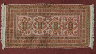 An Afghan rug with four pendant medallions on an ivory and rouge field within geometric design