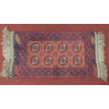 A Bokhara style rug with elephant pad motifs on a rouge field, within border with petal motifs.