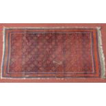 A Turkoman style rug with Tekkeh motifs on a rouge ground, within geometric bands,182x95cm
