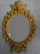 An oval bevelled wall mirror in gilt metal swag decorated frame. 45x30cm