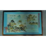 A framed and glazed Chinese abalone shell artwork depicting a temple on top of one of two mountains.