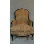 An oak framed Louis XV style armchair with floral carving and red and gold cheque upholstery, raised