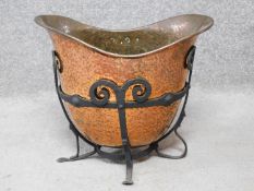 An Art Nouveau beaten copper helmet shaped coal bucket with wrought iron stand. H.37 W.43 D.27cm