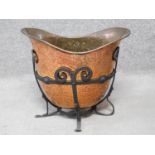 An Art Nouveau beaten copper helmet shaped coal bucket with wrought iron stand. H.37 W.43 D.27cm