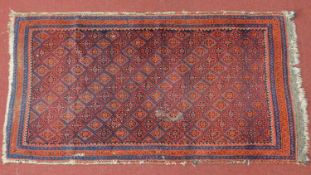 A Turkoman style rug with Tekkeh motifs on a rouge ground, within geometric bands,182x95cm