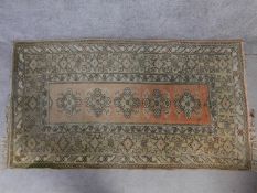 A Turkish style rug, with five pole medallions and geometric motifs on a rouge field, within multi