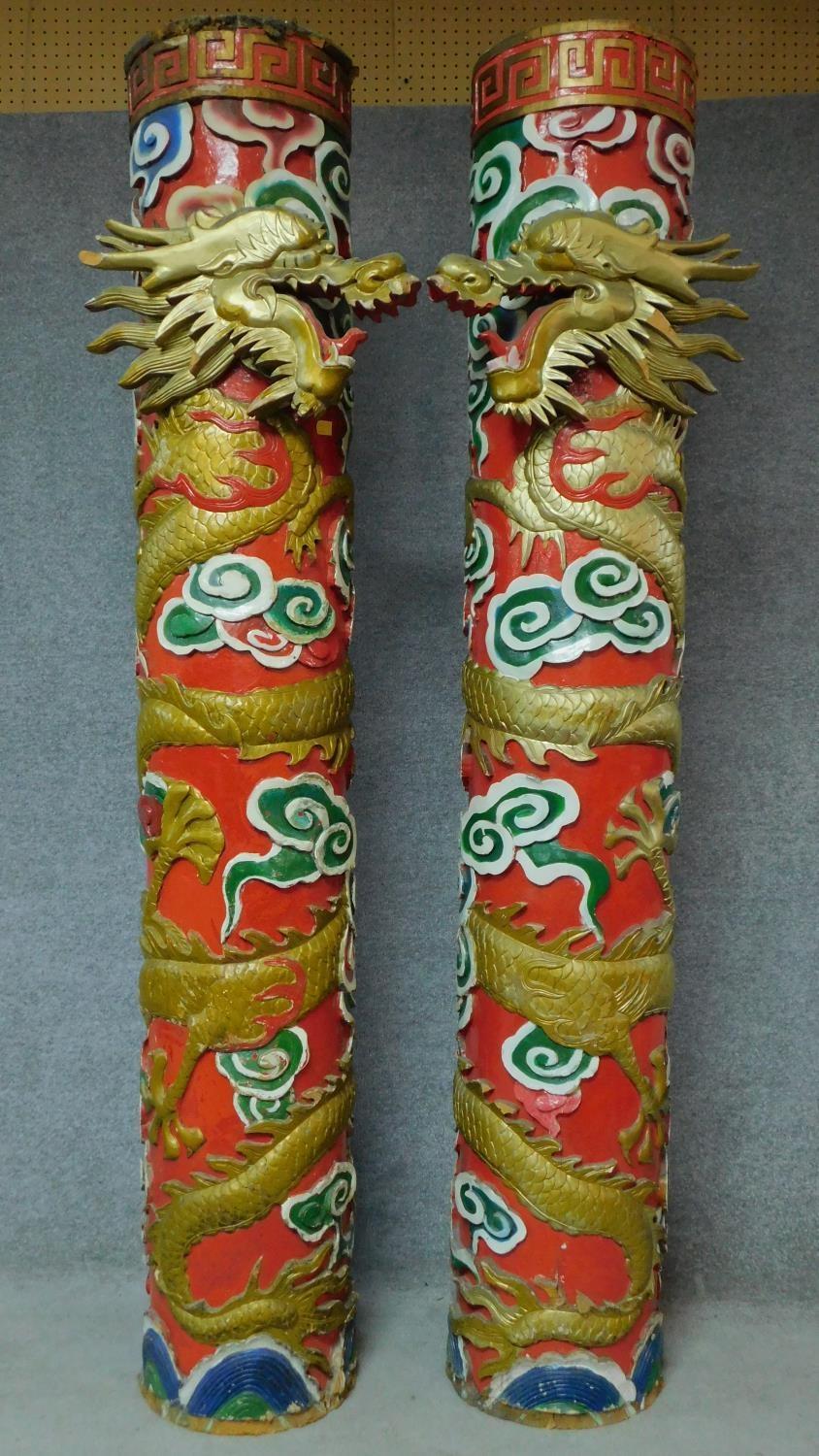 A pair of carved painted and gilded Chinese pillars with dragons wrapped around them and stylised