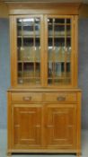 A late Victorian oak library bookcase with glazed upper section, pair of frieze drawers and panelled