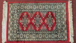 A Persian rug with triple pendant medallions, set on a rouge field with repeating geometric motifs