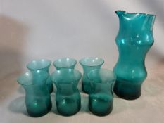 A set of six mid century blown glass turquoise tumblers with matching jug. Abstract design and
