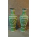 A pair of modern Kangxi style pale green and white glazed ceramic dragon vases. Signature to base.