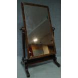 A William IV carved mahogany cheval mirror raised on swept supports on casters. 165x96cm