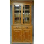 A late Victorian oak library bookcase with glazed upper section, pair of frieze drawers and panelled