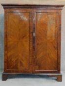 A Georgian mahogany press cupboard with quarter veneered and crossbanded panel doors enclosing