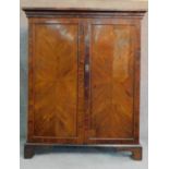 A Georgian mahogany press cupboard with quarter veneered and crossbanded panel doors enclosing